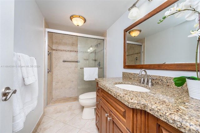 bathroom featuring vanity, toilet, tile patterned floors, and a shower with shower door