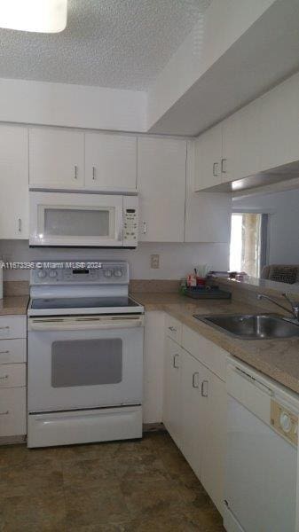 3204 Glenmoor Dr Unit 3204, West Palm Beach, FL 33409 - kitchen with white appliances, a sink, white cabinetry, and a textured ceiling