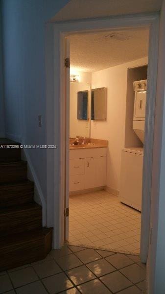 3204 Glenmoor Dr Unit 3204, West Palm Beach, FL 33409 - hall with stacked washer / dryer, light tile patterned floors, a sink, stairway, and baseboards