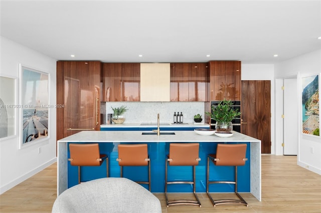 kitchen with an island with sink, a breakfast bar, and light wood-type flooring