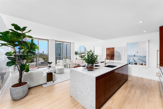 2678 Tigertail Ave Unit 1504B, Miami, FL 33133 - kitchen with a sink, light wood finished floors, a center island with sink, light stone counters, and open floor plan