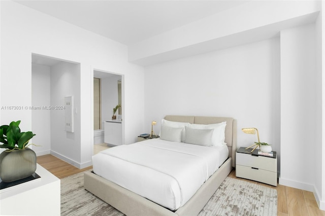 bedroom featuring ensuite bath and hardwood / wood-style floors