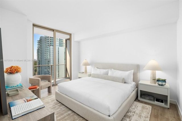 bedroom featuring expansive windows and light hardwood / wood-style floors