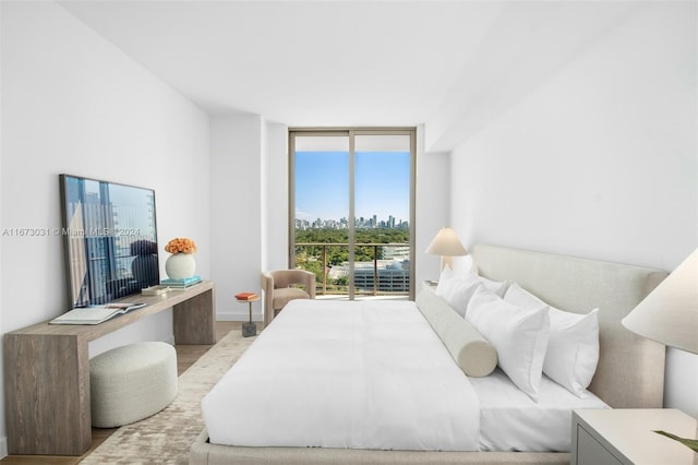 bedroom with a wall of windows, light hardwood / wood-style flooring, and access to exterior