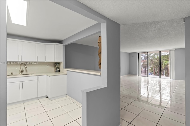 kitchen featuring white cabinetry, light tile patterned floors, a textured ceiling, and sink