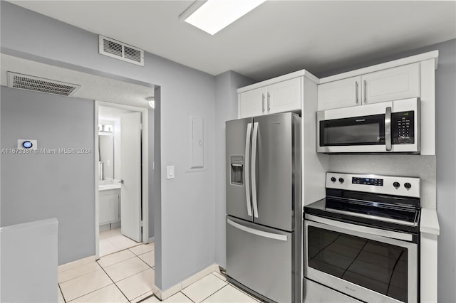 kitchen featuring white cabinetry, stainless steel appliances, and light tile patterned flooring