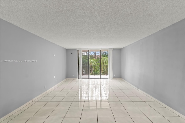 tiled spare room with expansive windows and a textured ceiling