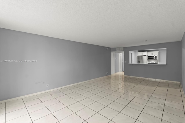 tiled spare room featuring a textured ceiling