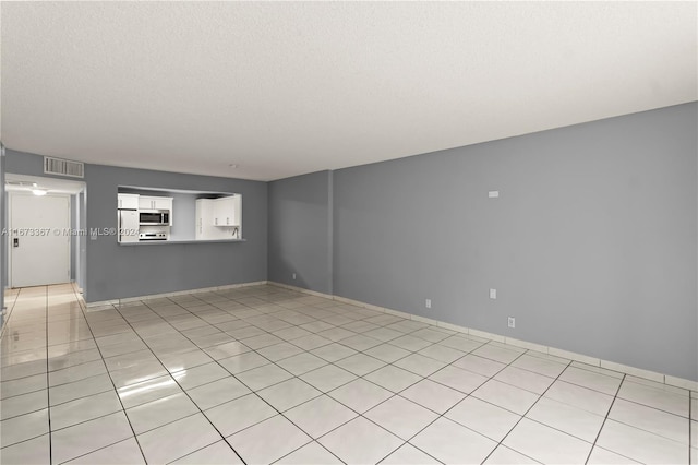 empty room with a textured ceiling and light tile patterned flooring