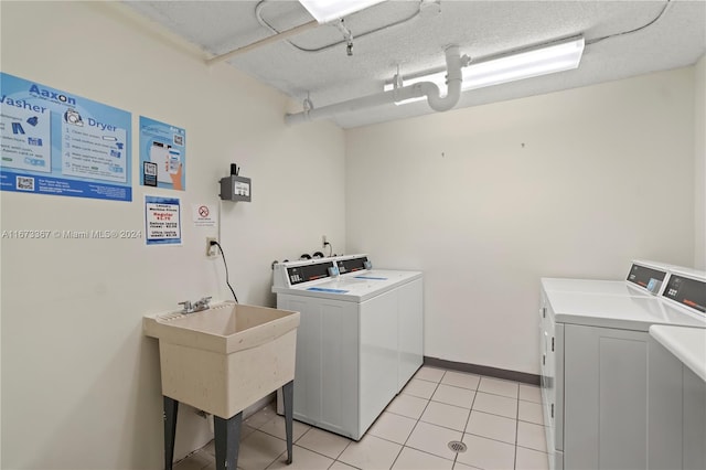 clothes washing area featuring sink, independent washer and dryer, a textured ceiling, and light tile patterned floors