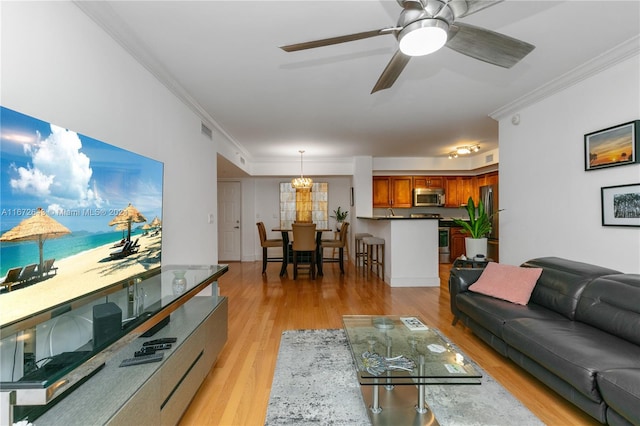 living room with crown molding, ceiling fan with notable chandelier, and light hardwood / wood-style flooring