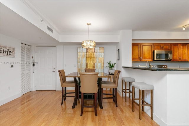 dining space with light hardwood / wood-style flooring, a chandelier, and crown molding