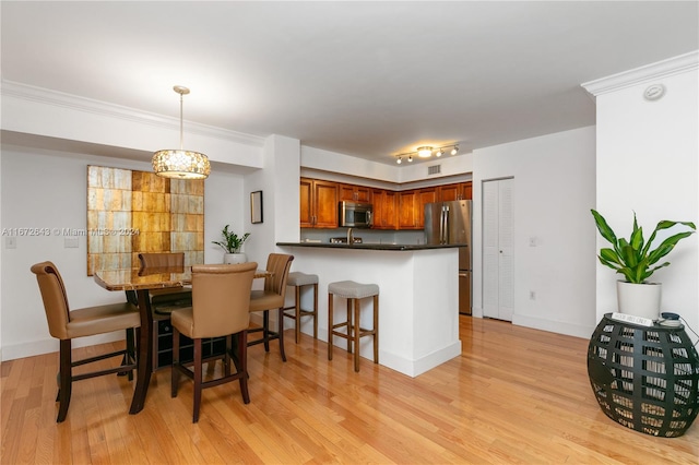 kitchen with kitchen peninsula, decorative light fixtures, light hardwood / wood-style flooring, stainless steel appliances, and a notable chandelier