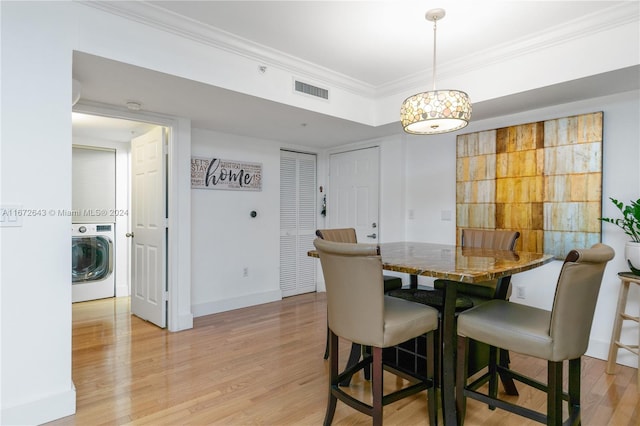 dining room with light wood-type flooring, ornamental molding, and washer / dryer