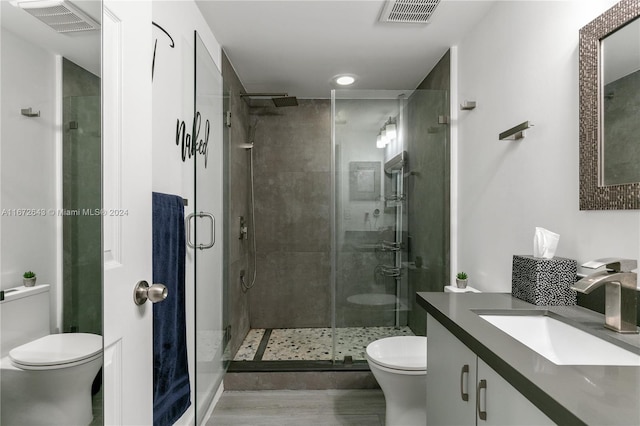 bathroom featuring vanity, toilet, a shower with door, and hardwood / wood-style flooring