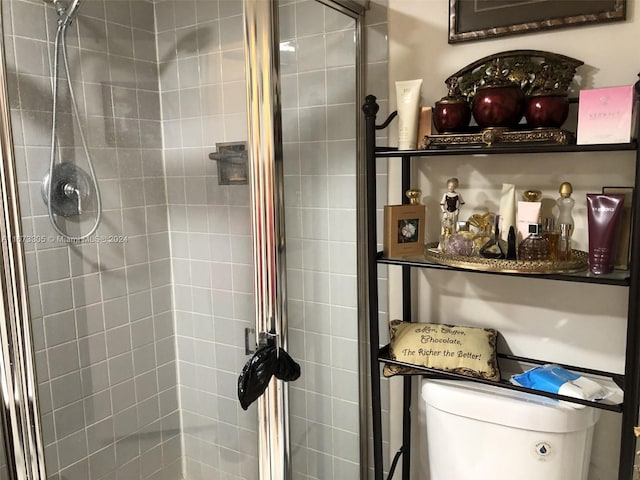 bathroom featuring a shower with door and toilet