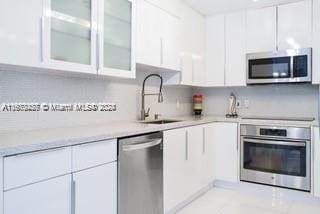 kitchen with appliances with stainless steel finishes, sink, and white cabinetry