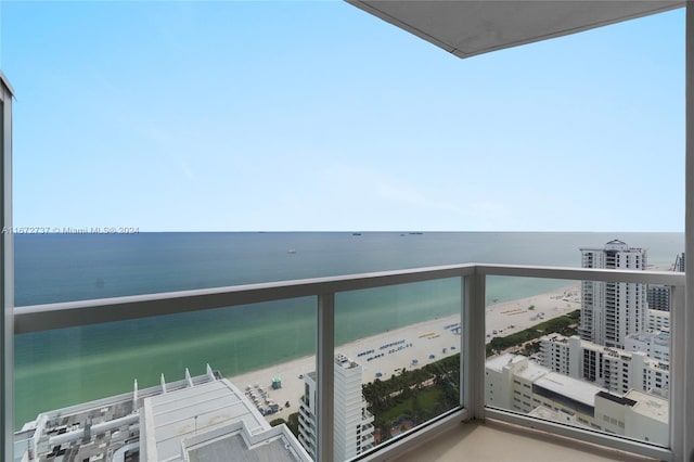 balcony with a water view and a view of the beach