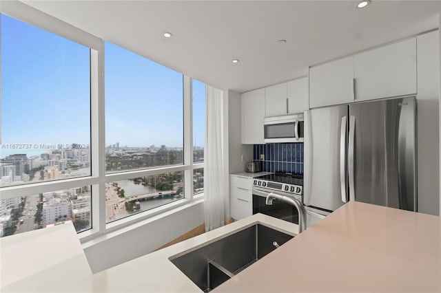 kitchen featuring appliances with stainless steel finishes, decorative backsplash, and white cabinets