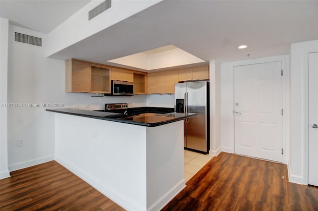 kitchen featuring hardwood / wood-style flooring, appliances with stainless steel finishes, and kitchen peninsula