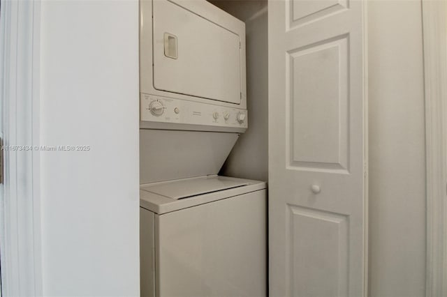 clothes washing area with stacked washing maching and dryer