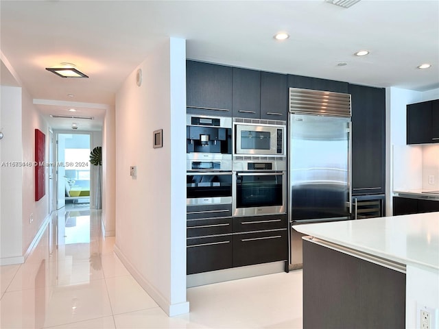 kitchen with built in appliances, light tile patterned floors, and wine cooler