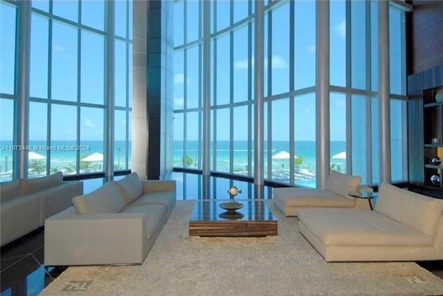 carpeted living room with a towering ceiling, a water view, and a healthy amount of sunlight