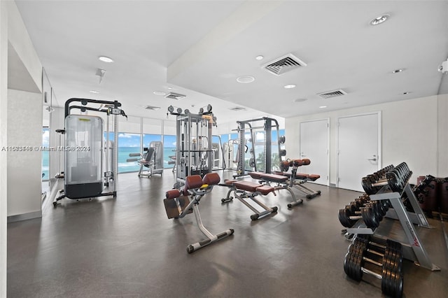 exercise room featuring a water view and expansive windows