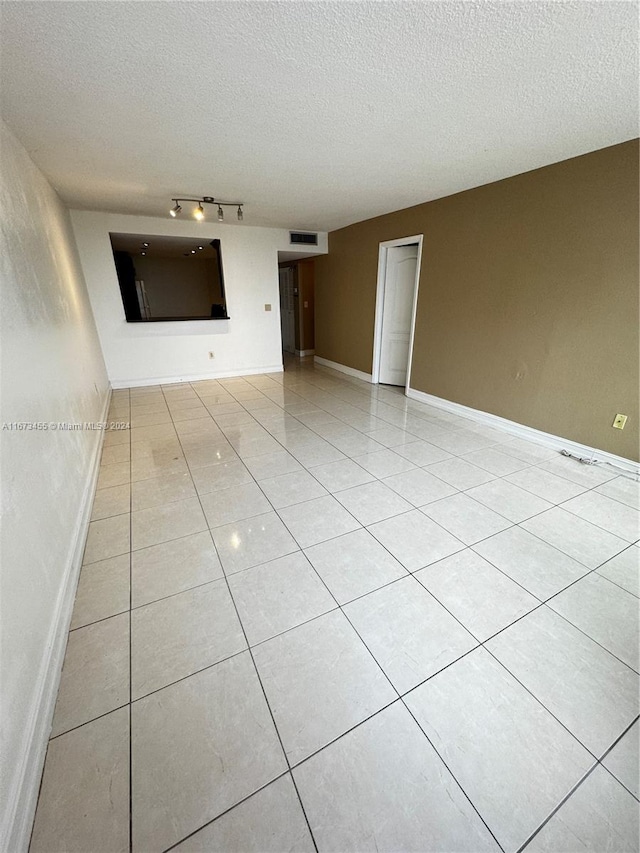 empty room with a textured ceiling and light tile patterned floors