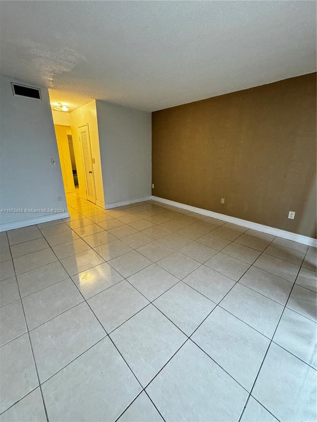 spare room featuring a textured ceiling and light tile patterned floors