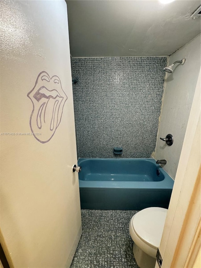 bathroom with tile patterned flooring, tiled shower / bath combo, and toilet