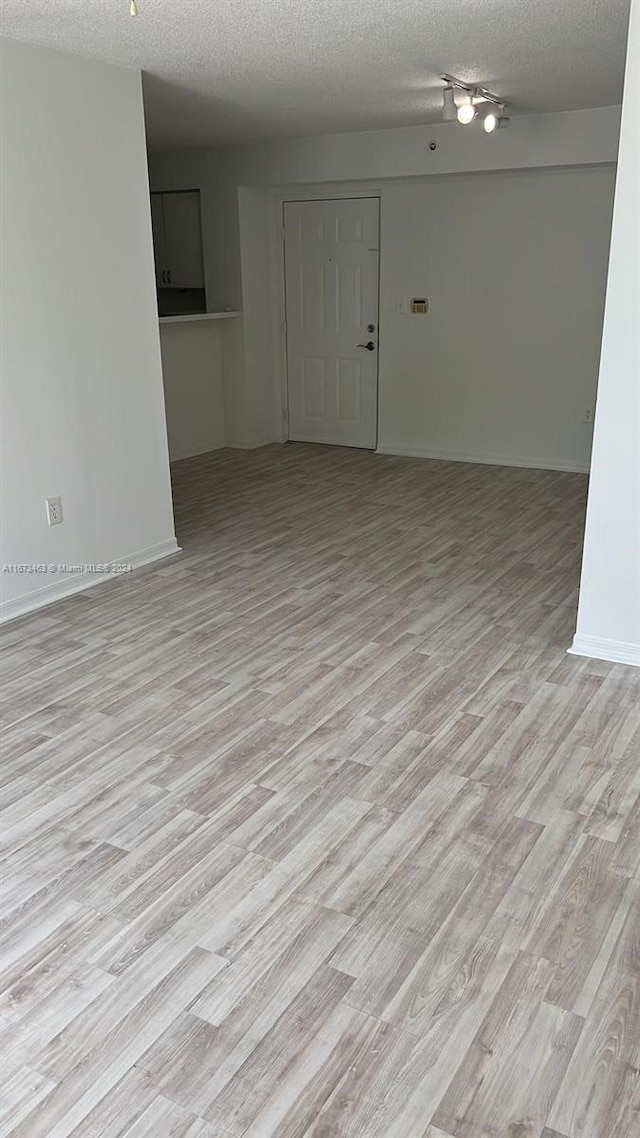 unfurnished room with a textured ceiling and light hardwood / wood-style floors