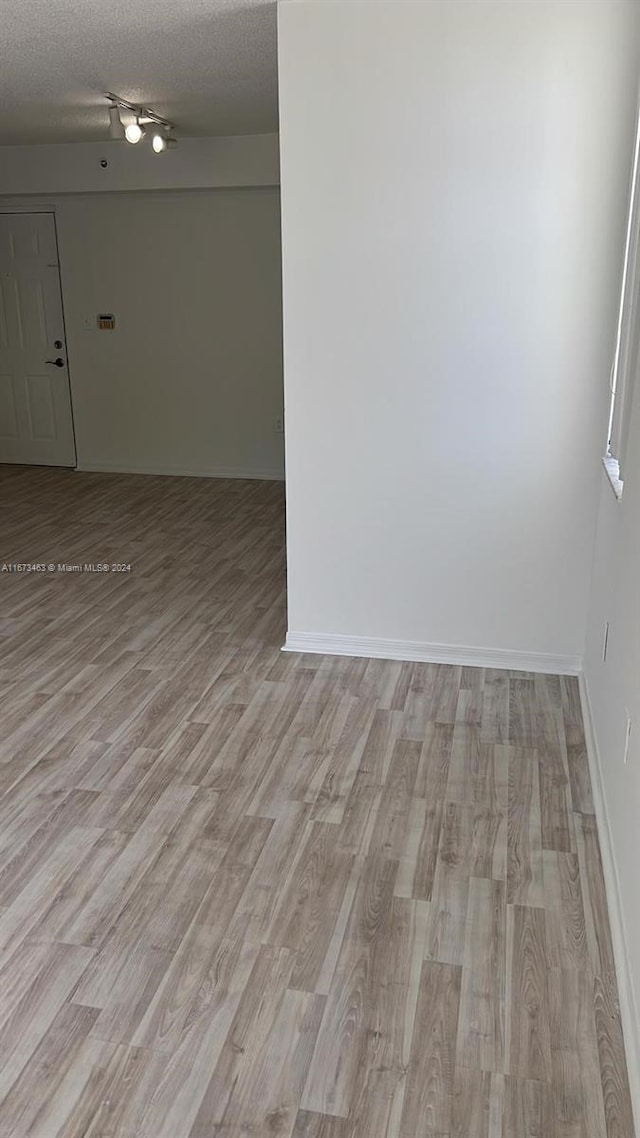 unfurnished room with a textured ceiling and light hardwood / wood-style flooring