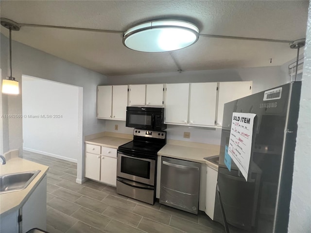 kitchen with pendant lighting, a textured ceiling, sink, white cabinets, and appliances with stainless steel finishes