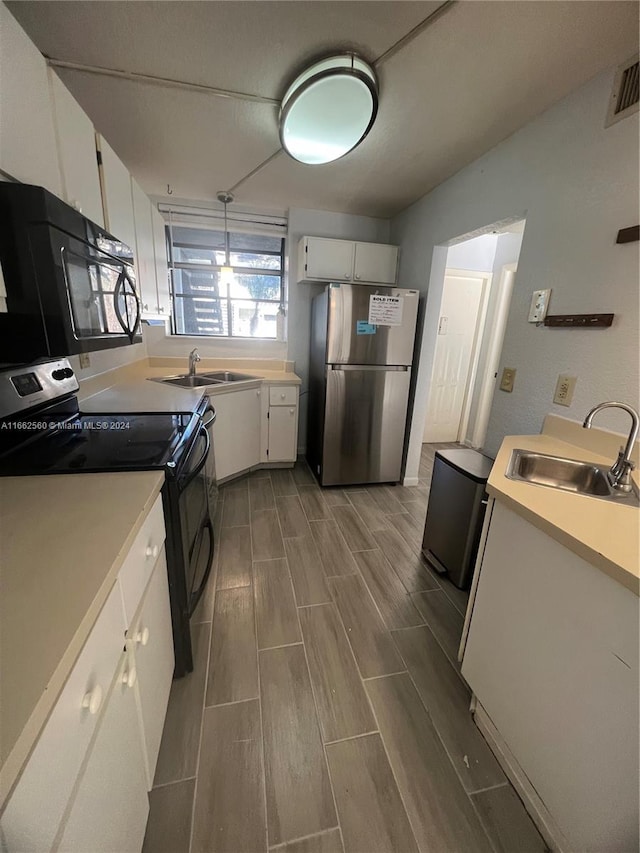 kitchen with wood-type flooring, white cabinets, sink, and black appliances