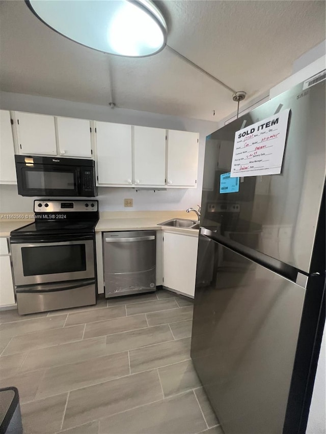 kitchen with white cabinetry, appliances with stainless steel finishes, hanging light fixtures, and sink