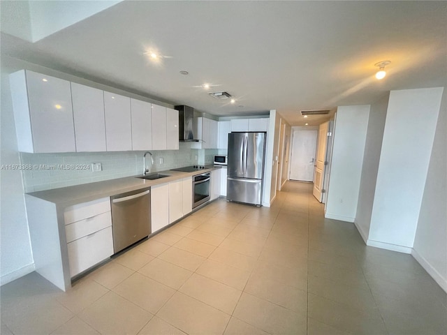 kitchen featuring white cabinets, sink, wall chimney exhaust hood, backsplash, and stainless steel appliances