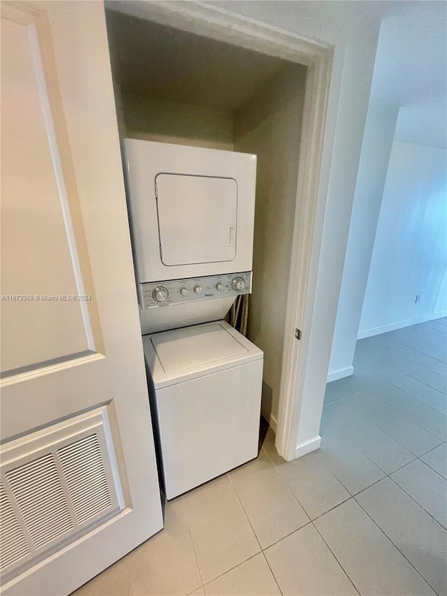 washroom with stacked washer / dryer and light tile patterned floors