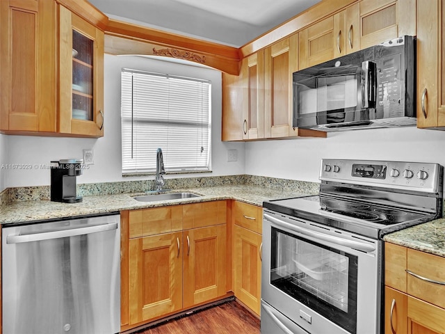 kitchen featuring stainless steel appliances, sink, light stone counters, and dark hardwood / wood-style floors