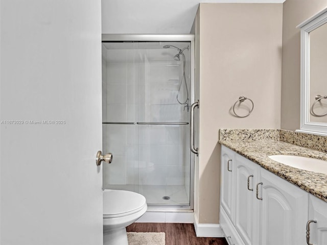 bathroom with hardwood / wood-style flooring, vanity, toilet, and a shower with door