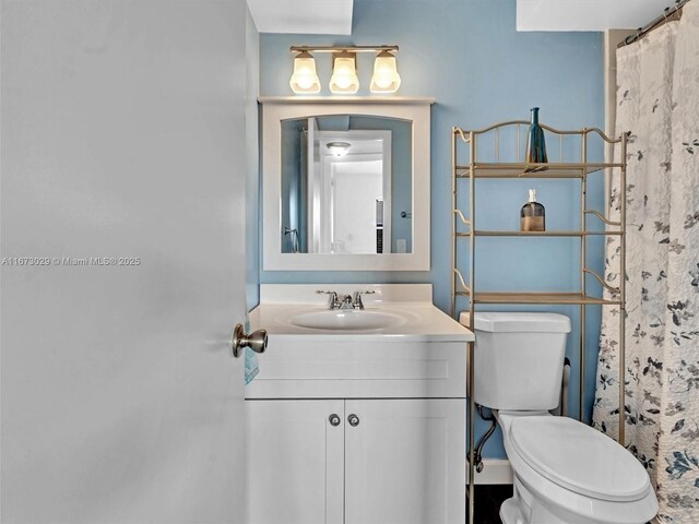 bathroom featuring vanity, curtained shower, and toilet