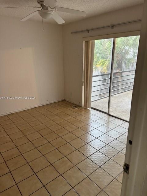 tiled spare room with a textured ceiling and ceiling fan