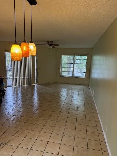 tiled empty room featuring ceiling fan and a textured ceiling