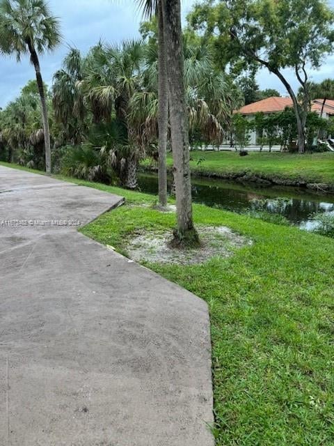 surrounding community featuring a lawn and a water view