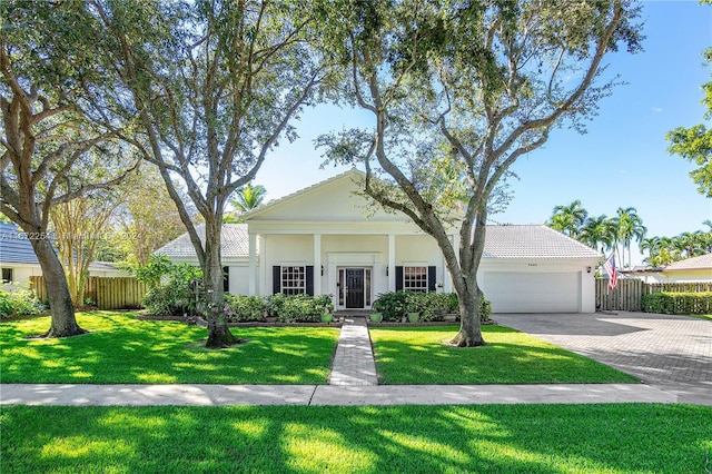 view of front of home featuring an attached garage, fence, decorative driveway, stucco siding, and a front lawn