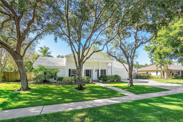 view of front facade with a garage, concrete driveway, fence, a front lawn, and stucco siding