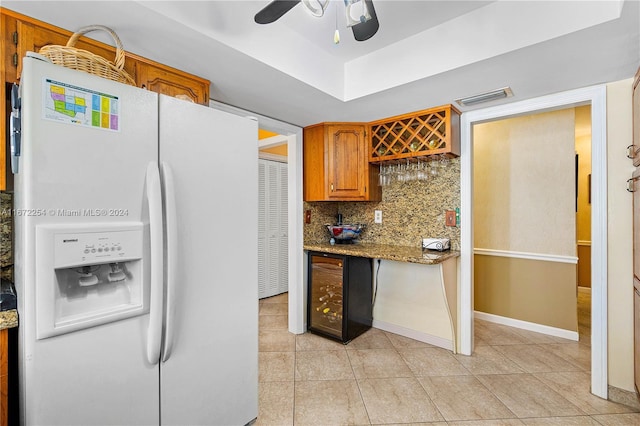 kitchen featuring brown cabinets, light tile patterned floors, visible vents, decorative backsplash, and white fridge with ice dispenser