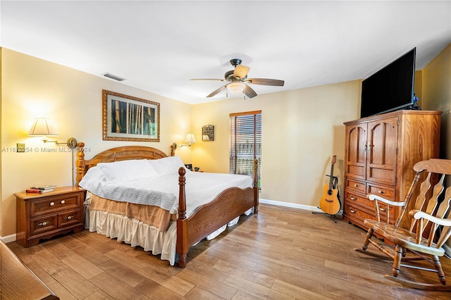 bedroom featuring baseboards, a ceiling fan, visible vents, and light wood-style floors