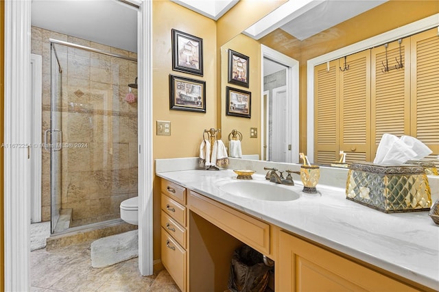 bathroom featuring toilet, a stall shower, a skylight, and vanity