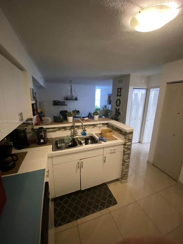 kitchen with a textured ceiling, kitchen peninsula, and white cabinets